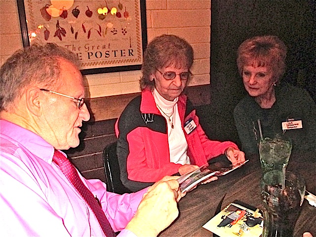 Marty Defatte looks at old reunion pictures with Laurie Janot and Sue DeGarmo.