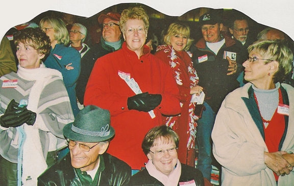 Janice Schommer Kuhloff, Judy Wilda Amundsen, Judy Cloutier Chiapetta and Barb Griffith Eckert stand up and cheer.  Harry and Margy Draves Park from Allen, TX look on.